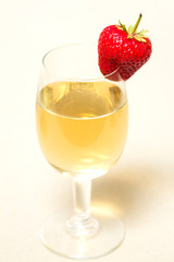 Red and ripe strawberry on glass with a yellow drink