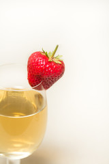 Red and ripe strawberry on glass with a yellow drink