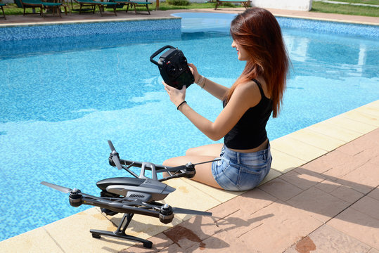 girl fly drone with remote control by the swimming pool