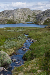 Fototapeta na wymiar Scenic view of mountain stream and lake with mountain peaks in the background, Rogaland, Norway. 