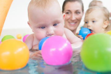 Fototapeta na wymiar Mums and babies having fun at infant swimming course