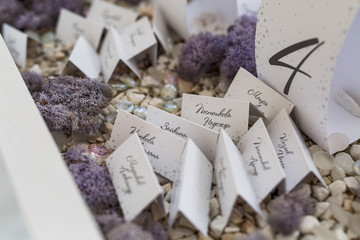 Paper cards with guests' lie on white decorative stones