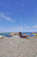 Fototapeta na wymiar Un couple prépare son voilier sur la côte à Plougrescant