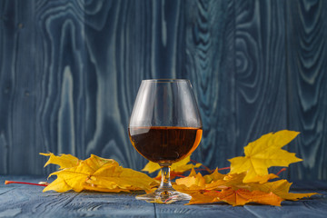 Glass of whiskey on table with leaves