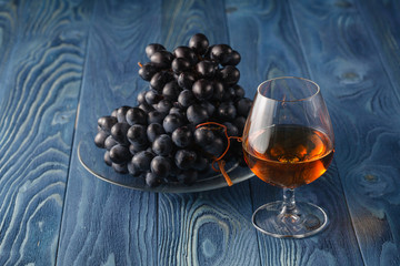 Cognac glass with grape on blue table