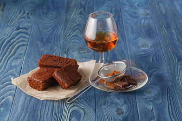 Glass of rum on wooden tray with chocolate brownies in the backg