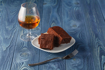 Glass of rum on wooden tray with chocolate brownies in the backg