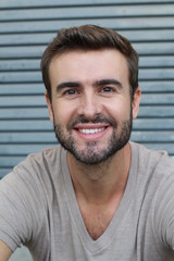 Portrait of good looking smiling bearded man with perfect white teeth. Young beautiful Caucasian male model with healthy smile posing in studio over gray background