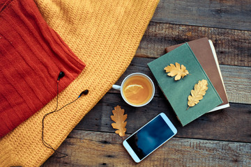 Tea with a lemon and autumn leaves on vintage wood background -
