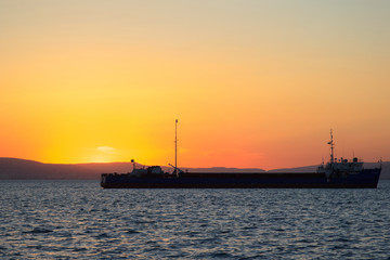 Fototapeta premium Sunset at sea with cargo ships in the background