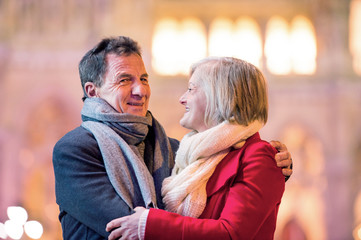 Senior couple walking in night city. Winter, Historical building