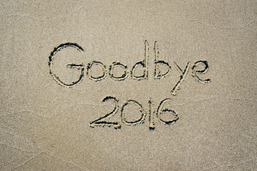 Goodbye 2016 text message handwritten on sand background. Holiday postcard template.