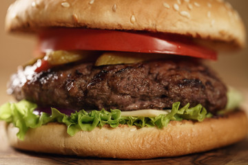closeup fresh homemade burger with marble beef, cheese and vegetables on olive board