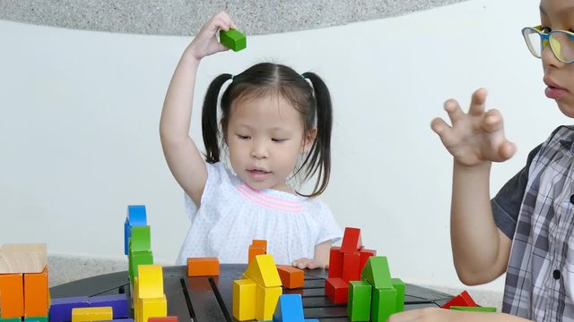 Asian siblings playing blocks together 