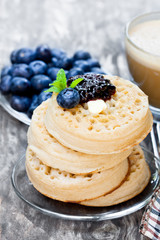 Hot  toasted crumpets on the wooden table with blueberries and j