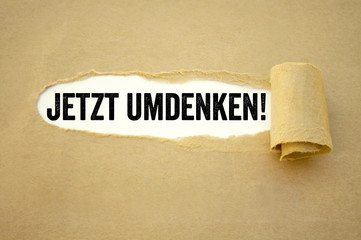 Abgerissenes Papier mit Jetzt umdenken