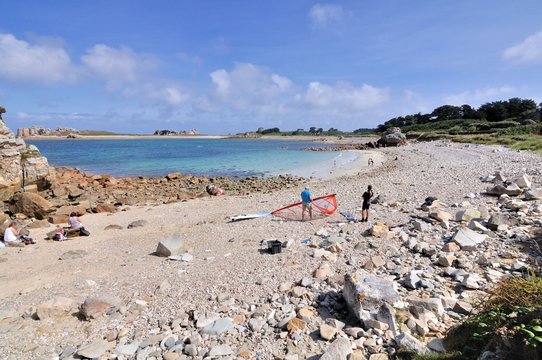 Deux hommes préparent une planche à voile sur une plage à Plougrescant en Bretagne