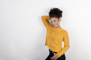 Smiling young woman standing against a wall in a trendy sweater