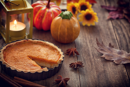 Thanksgiving pumpkin pie with lantern on wooden background