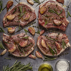 Raw pork chops with spices on a metal baking sheet.