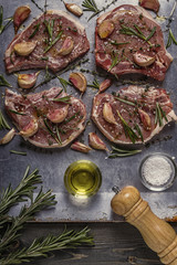 Raw pork chops with spices on a metal baking sheet.