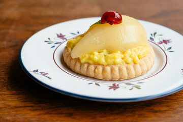 Mini Gingered Pear Tart, garnished with candied cherry and lemon balm leaf