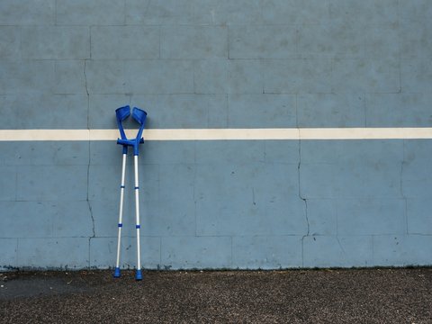 Medical crutch at blue training tennis wall  on outdoor stadium players court,
