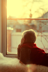 Ребенок у окна смотрит на закат зимой
