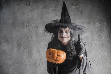 Halloween witch holding a pumpkin