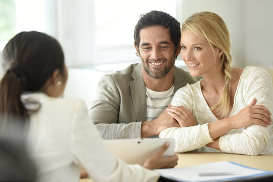Cheerful married couple meeting financial adviser