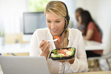 Busy customer service manager eating lunch in office