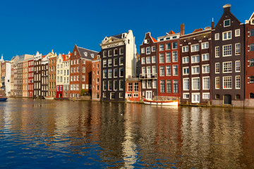 Naklejka premium Beautiful typical Dutch dancing houses at the Amsterdam canal Damrak in sunny day, Holland, Netherlands.