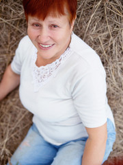 Portrait of smiling mature red hair woman in hay