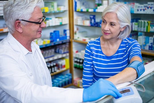 Pharmacist checking blood pressure of customer