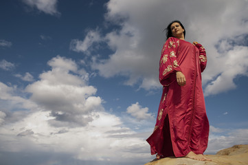 Obraz na płótnie Canvas bonita mujer de rojo bajo un fondo azul lleno de nubes