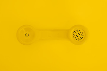A Retro Yellow Telephone Handset on Yellow Background
