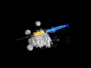 Cocaine drug powder pile, pills and injection on black background