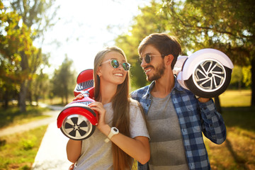 young man and woman riding on the Hoverboard in the park. content technologies. a new movement....