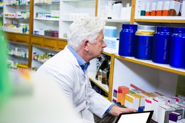 Pharmacist holding digital tablet while checking medicine