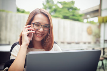 Young asian women smiling happy using laptop and smartphone connected to social online at home