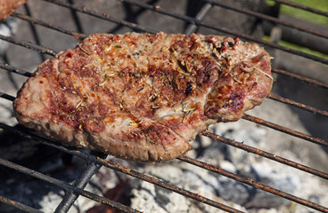 Grilled beef steak cooking on barbecue grill