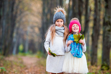 Two adorable girls in forest at warm sunny autumn day