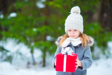 Adorable little girl with christmas box gift in winter day outdoors