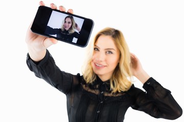 Smiling woman clicking photo from mobile phone