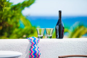Glasses, bottle of tasty wine and swimsuit on balcony in greek island with view of sea