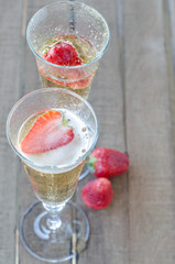 two glasses of champagne with strawberies on wooden table