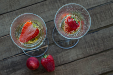 two glasses of champagne with strawberies on wooden table