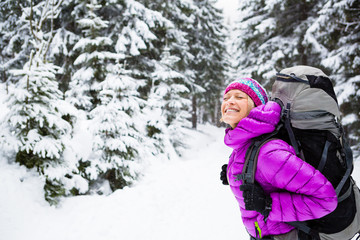 Fototapeta na wymiar Happy woman walking in winter forest with backpack