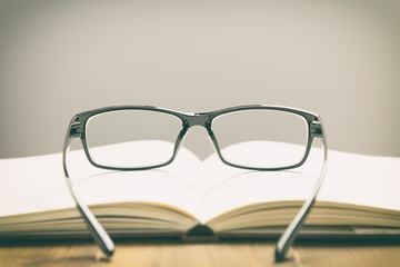 Eyeglasses and books on wood table, soft focus