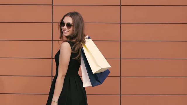 Portrait of shopping woman turning around with shopping bags. Slow motion